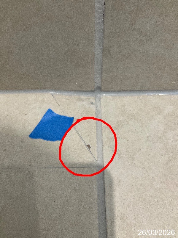 Chip at a tile corner marked with a red circle and blue tape