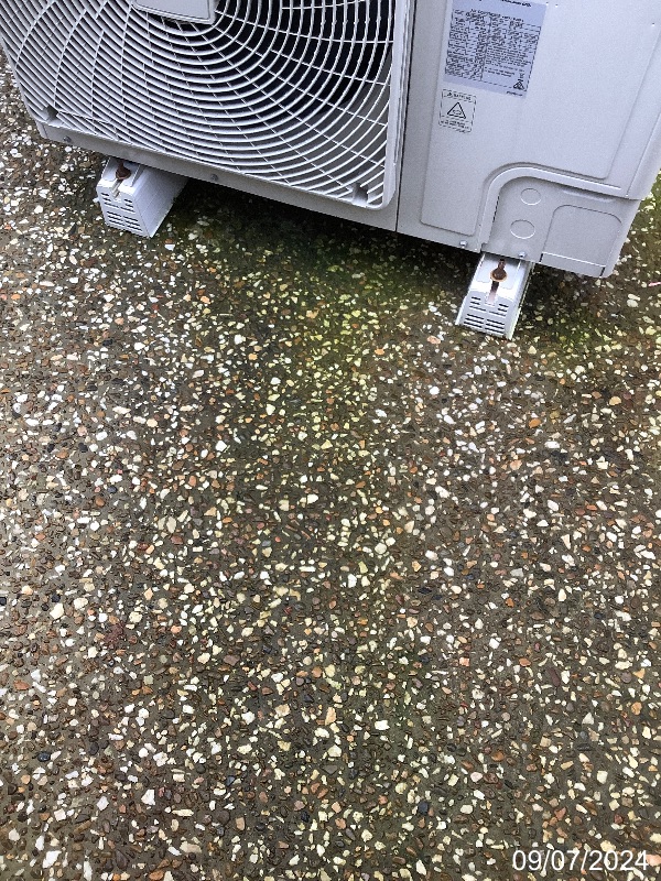 Damp and stained concrete beneath an outdoor air-conditioning unit