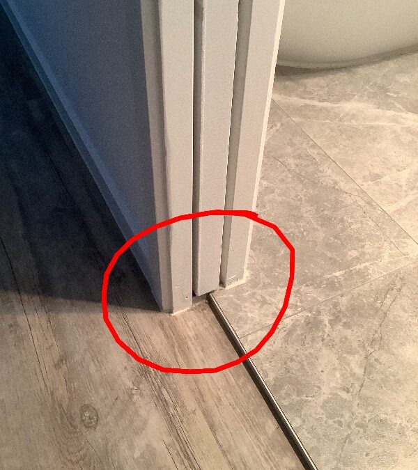 Red inspection circle around the base of a bathroom cavity sliding door at a tiled threshold