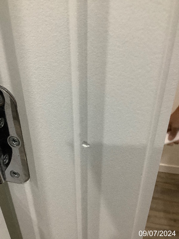Close-up of a small area of damaged white paint on a door frame beside the latch