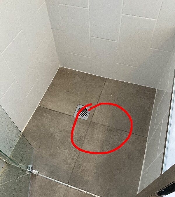 Water pooling on shower floor beside the waste, marked with a red circle