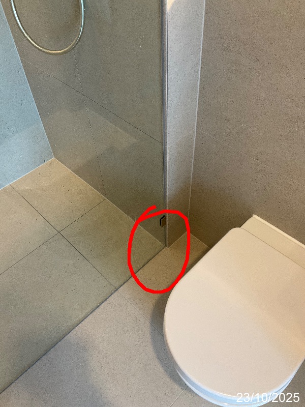 Base of shower screen beside a toilet marked for a reported leak
