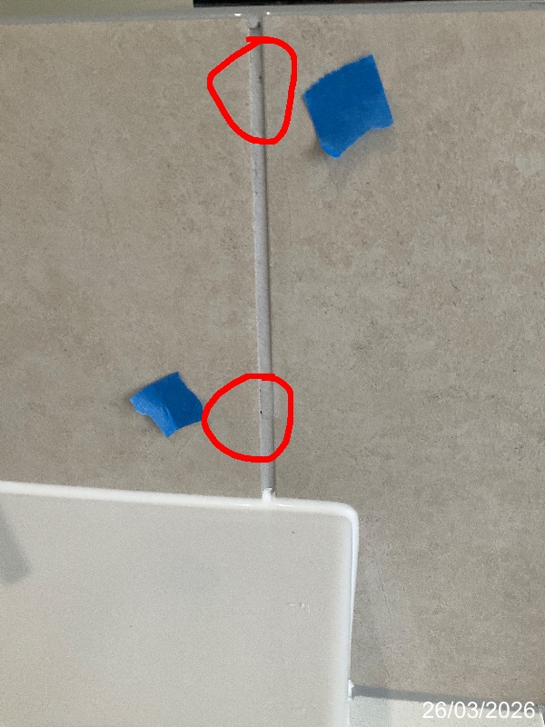 Red circles marking pinholes in a vertical tile grout joint