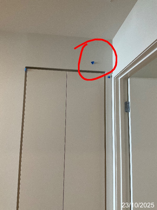 Plaster above a cupboard marked with a red circle and blue tape